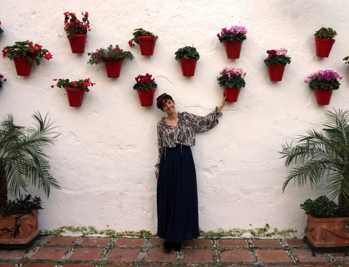 Alicia, Oh My Good Guide Owner, standing by the wall decorated with flower pots