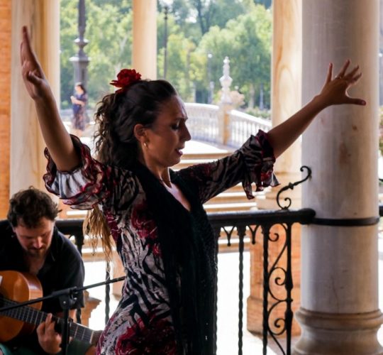 Woman dancing flamenco while a man plays guitar